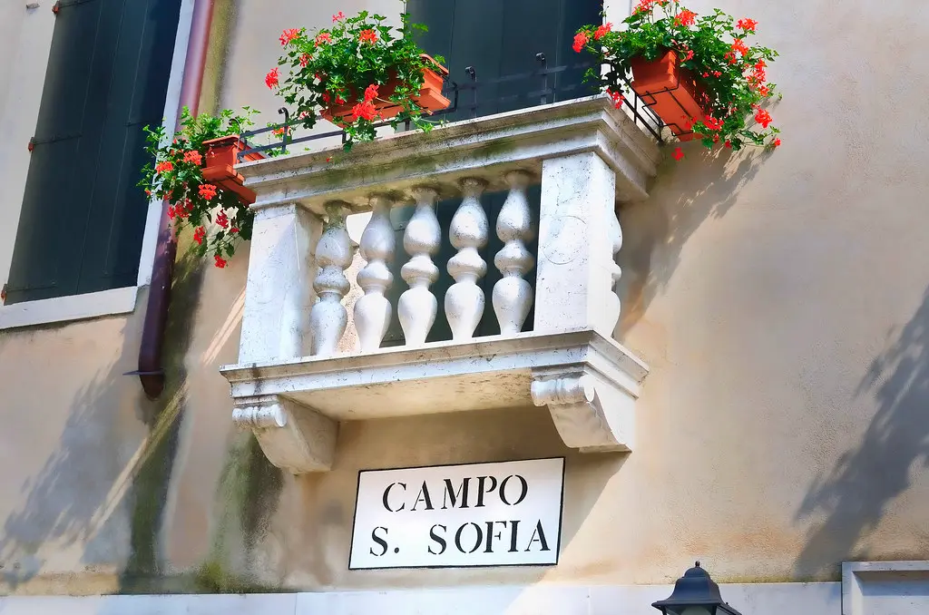 Close-up of a folding balcony chair beside a narrow metal table on a small balcony.