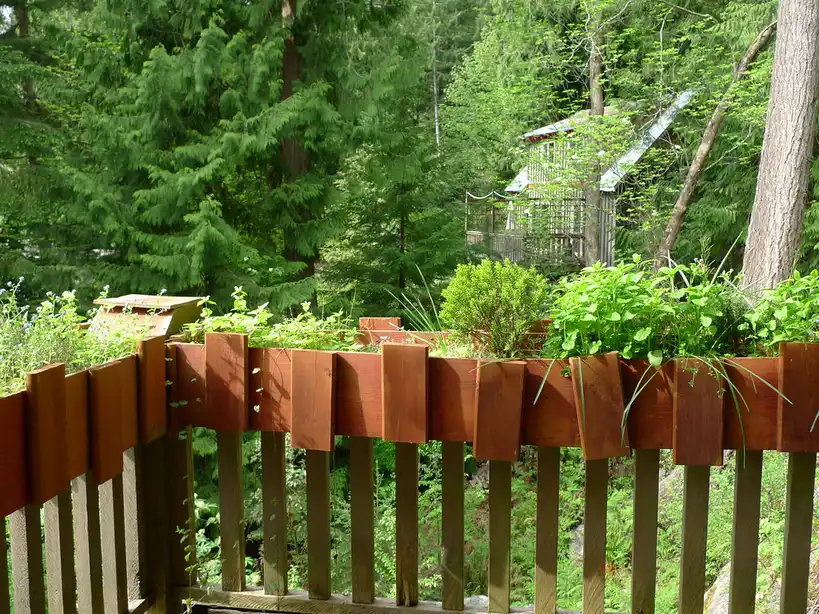 Hands adjusting a balcony planter bracket on a metal railing in daylight