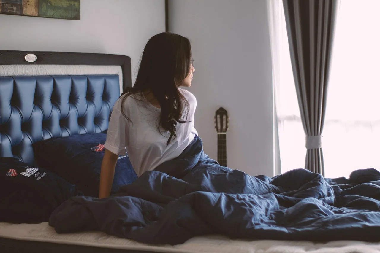 Calm bedroom with pale blue-gray walls, neutral bedding, and soft natural morning light