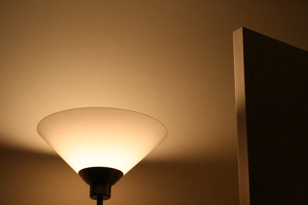 Bedside lamp beside a book and dimmer switch on a bedroom nightstand