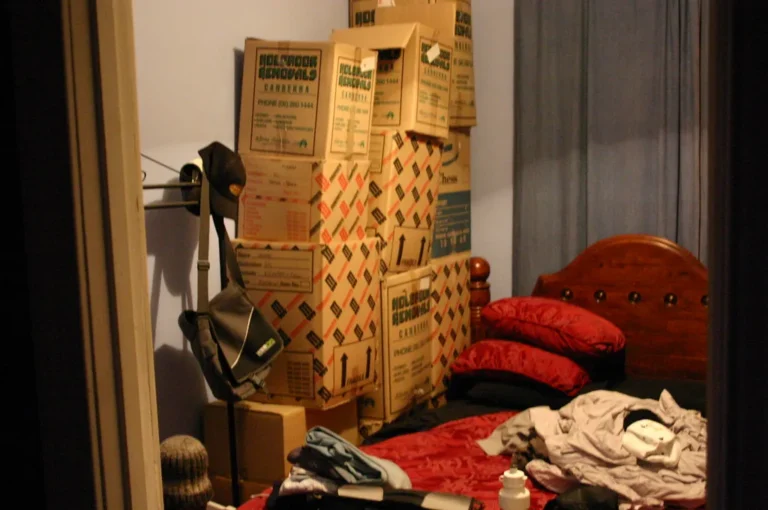 Small bedroom with under-bed bins, a drawer nightstand, wall shelf, and woven basket for bedroom storage ideas.