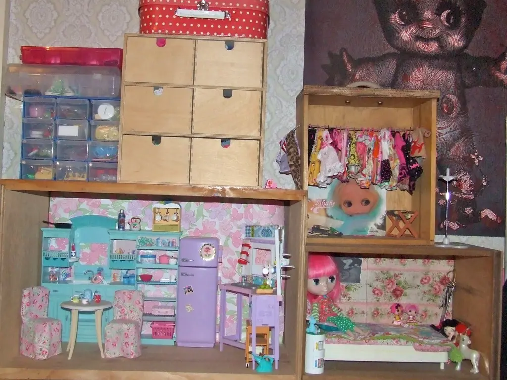 Hand sliding a fabric storage bin under a bed for seasonal clothes in a small bedroom.