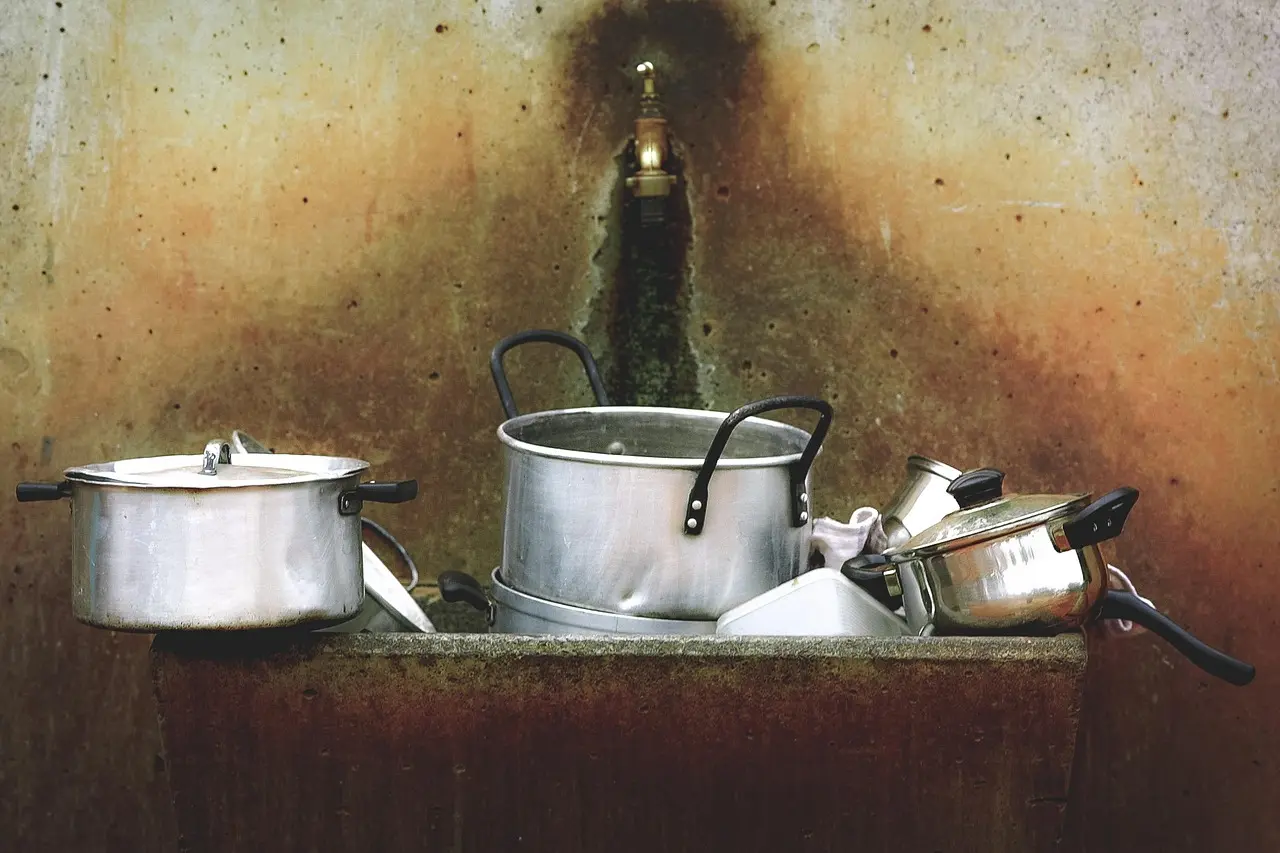Budget cookware arranged in a first-apartment kitchen beside a compact stove and limited cabinet space