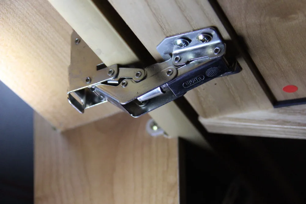Hand adjusting a soft-close cabinet hinge on a frameless cabinet door