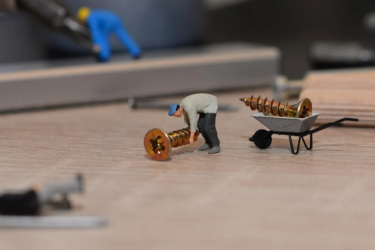 Cabinet screws, drill, and plywood cabinet panels laid out on a carpenter’s workbench