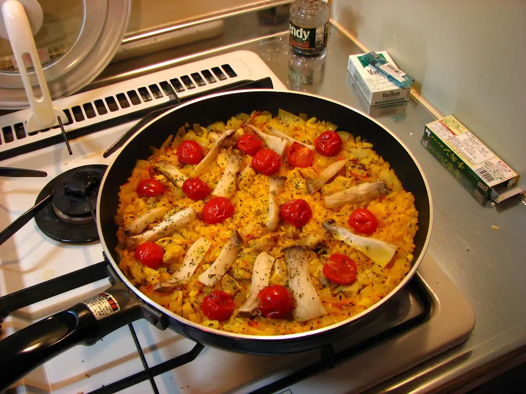 Hand checking a nonstick frying pan beside handwritten cooking notes