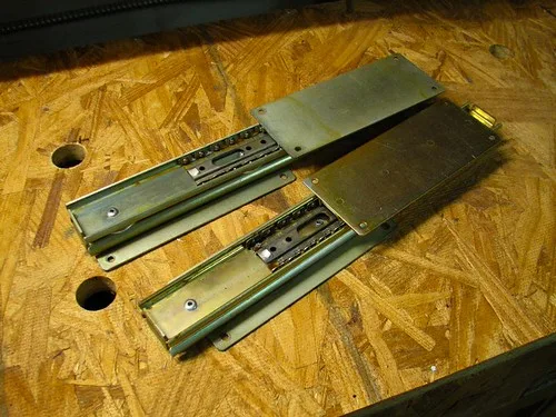 Heavy wooden drawer on metal drawer slides in a workshop bench under natural light