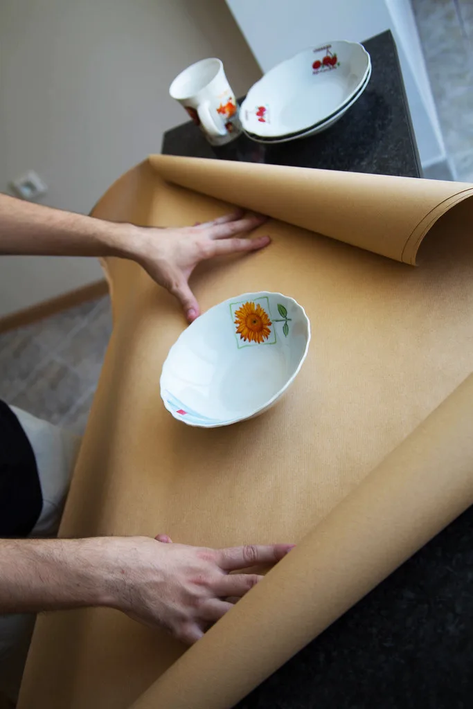 Bubble-wrapped plate fitted into a padded shipping box with measuring tape