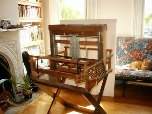Hands wrap a bed frame rail with stretch film, foam padding, and cardboard edge guards