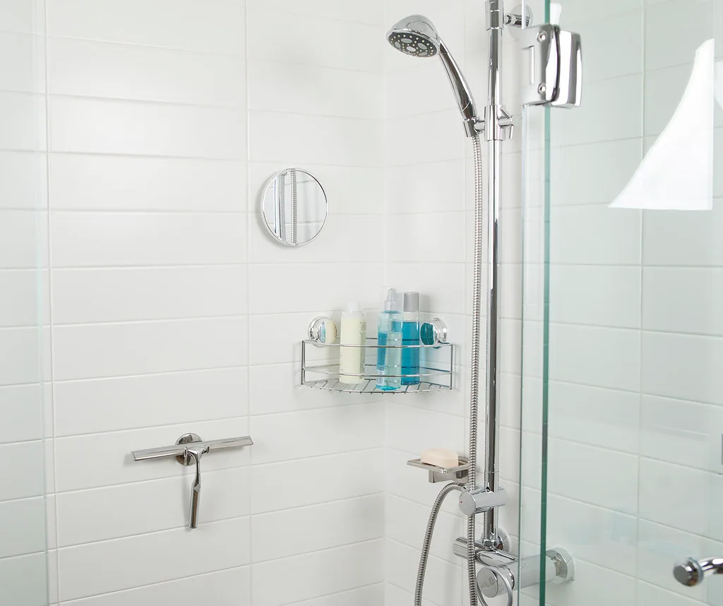 Hand using a compact shower squeegee on a glass shower door