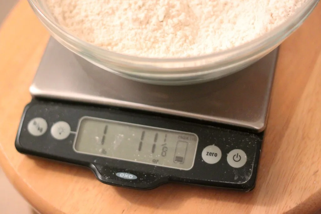 A digital kitchen scale weighing cocoa powder in a bowl during Valentine brownie prep