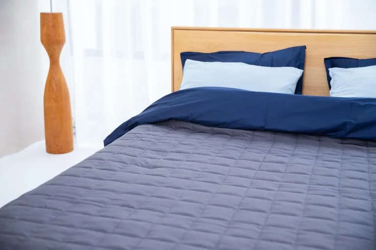 Futon mattress on a wooden base in a sunlit bedroom with bedding nearby