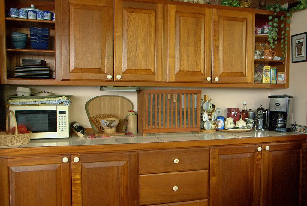 Installer aligning a kitchen cabinet box with a level and drill during setup.