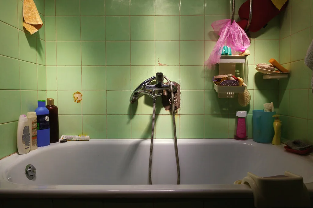 Close-up of a Moen Adler bathroom faucet spout and handle with water spots