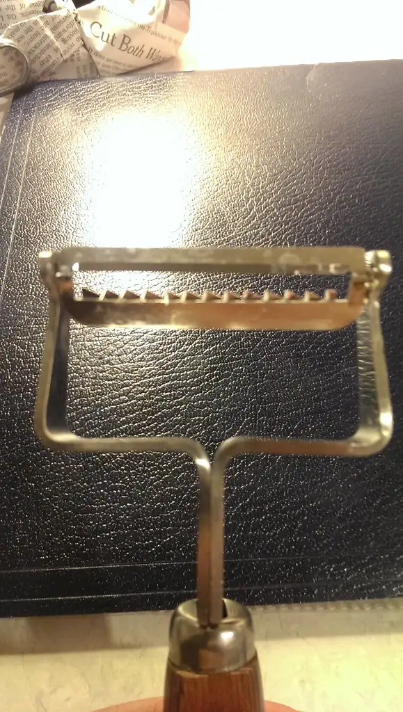 A cracked pan scraper held beside a scratched skillet edge in natural light