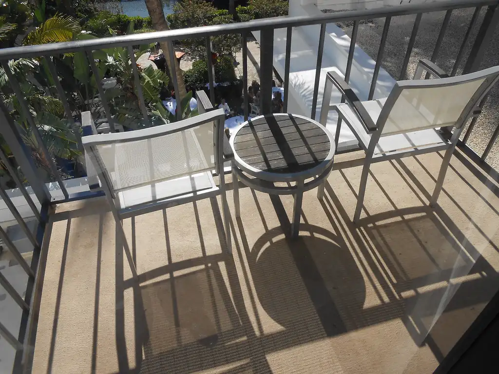 A folding chair collapsed and stored beside a balcony planter