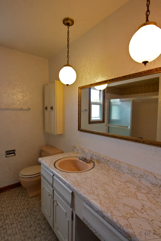 Contractor measures a shower niche during a bathroom remodel beside tile samples and waterproofing.