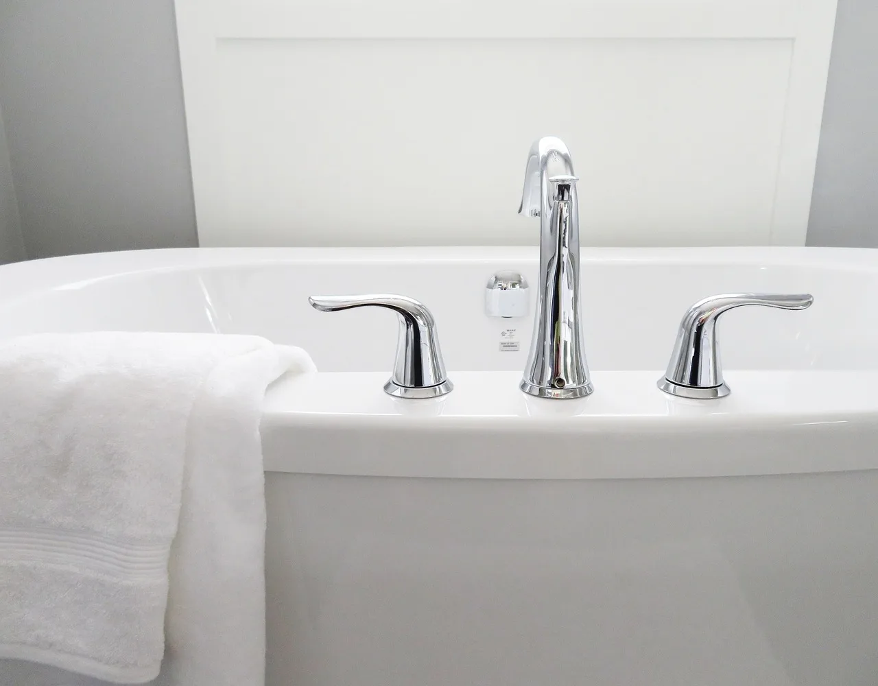 Homeowner and contractor comparing a worn bathtub in a small bathroom with repair materials nearby