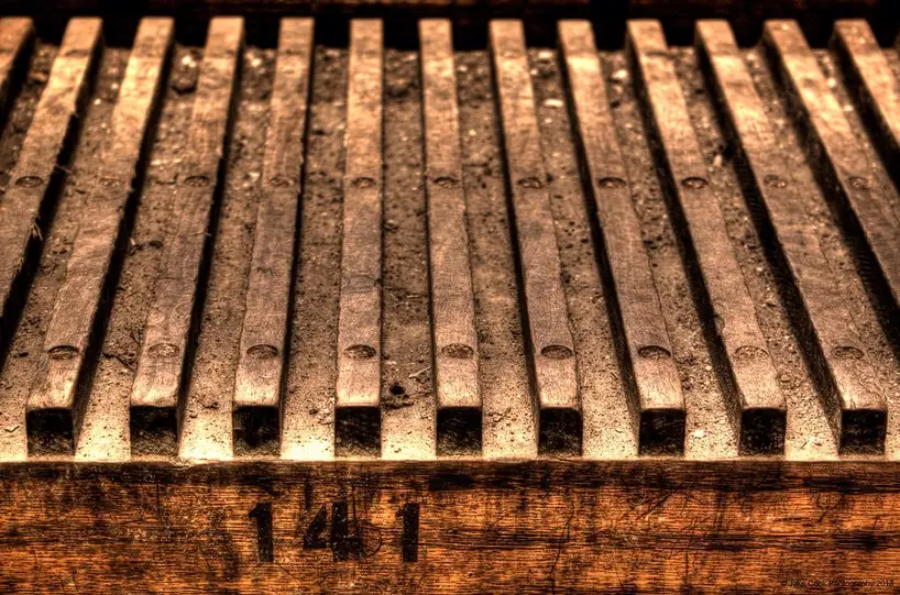Person comparing bed frame strap repair parts beside a metal bed frame in natural light