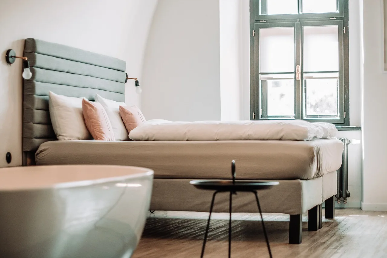 Stylish bedroom with upgraded headboard, layered rug, neutral bedding, and natural morning light