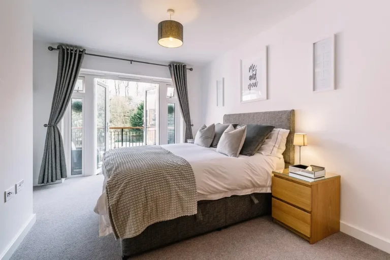 A bedroom furniture set with a bed, nightstands, dresser, and bench in a bright modern room.