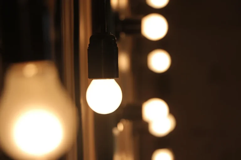 Modern bedroom with ceiling light, bedside lamps, and a person comparing light bulb packages