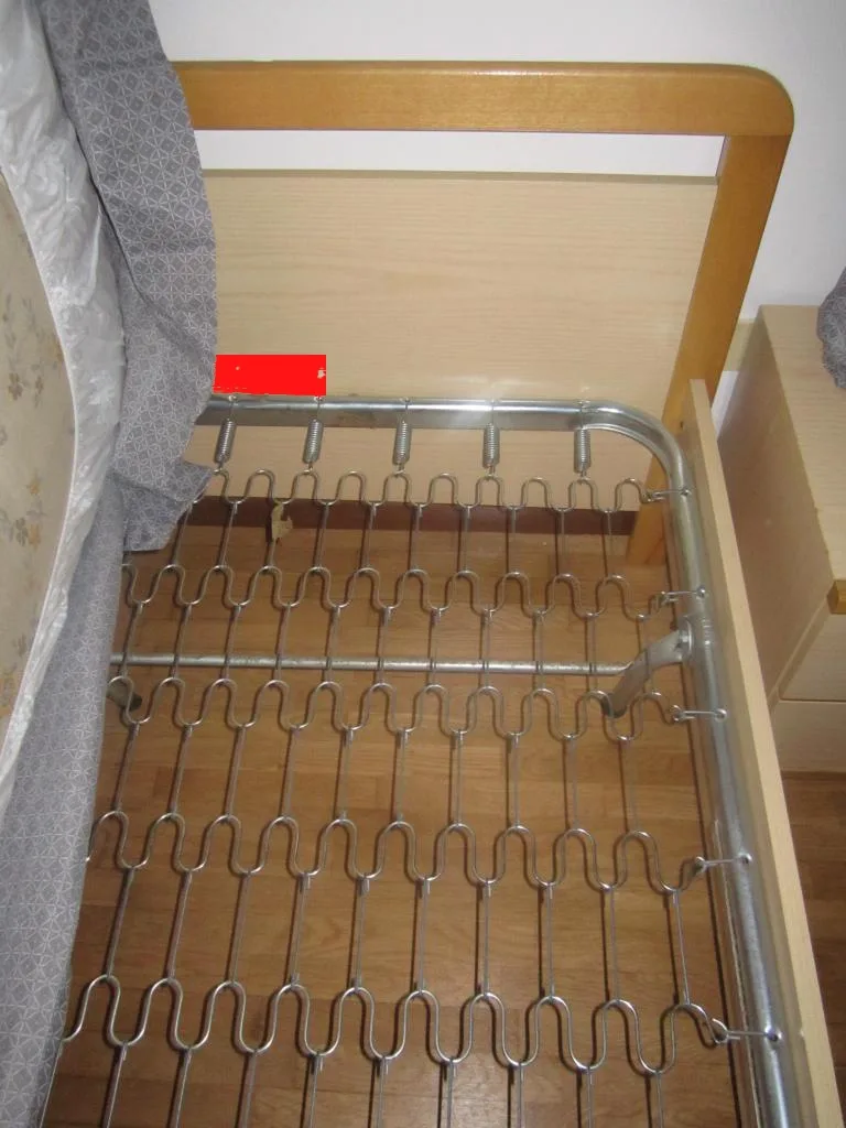 Close-up of bed slats with a hand checking a cracked edge