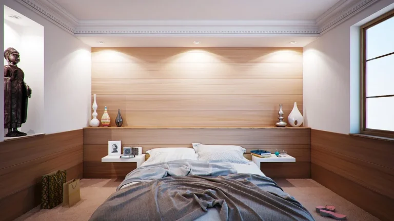 A softly lit bedroom with greige walls, a bed with linen bedding, and natural light from one window.