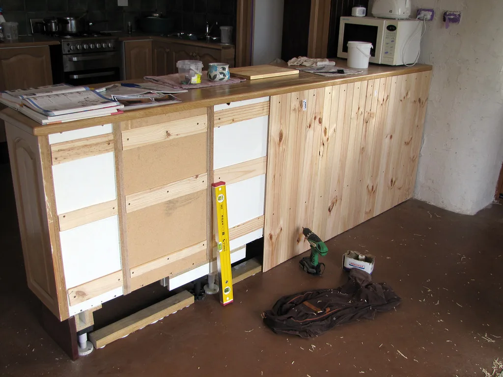 Person inspecting cabinet shelf pins inside a worn kitchen cabinet under natural light