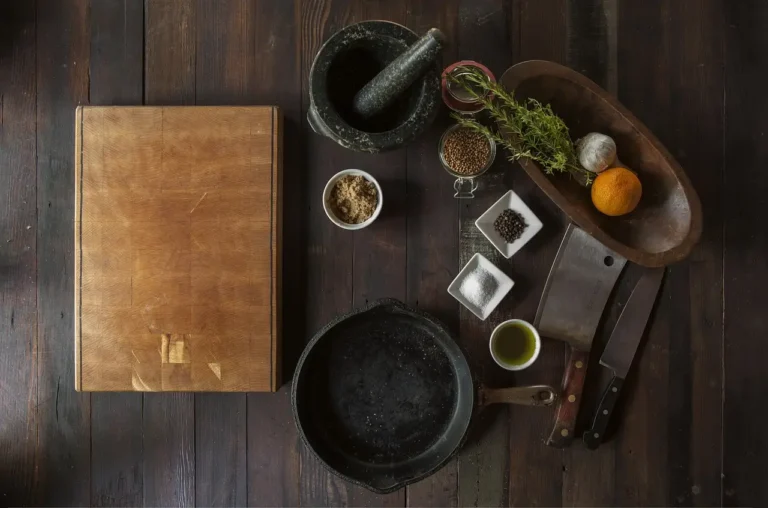 Old cookware and a restoration kit on a kitchen workbench, including cast iron, stainless steel, and nonstick pans.
