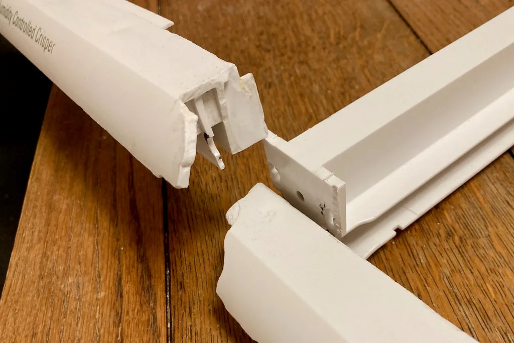 Hands replace a worn drawer guide with screws and a screwdriver nearby.