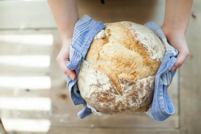 Dutch ovens and a rustic bread loaf on a wooden kitchen counter in natural light