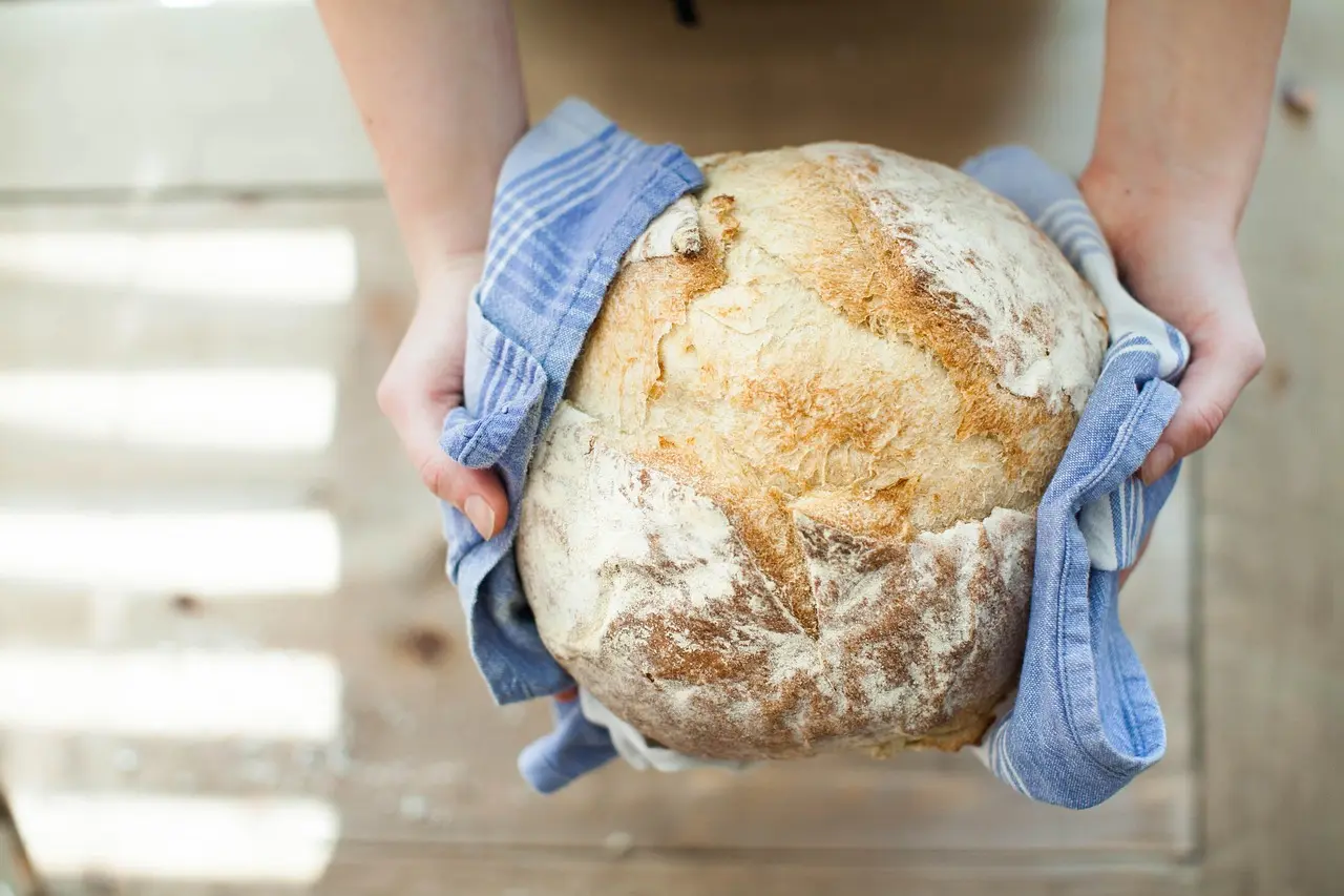 Dutch ovens and a rustic bread loaf on a wooden kitchen counter in natural light