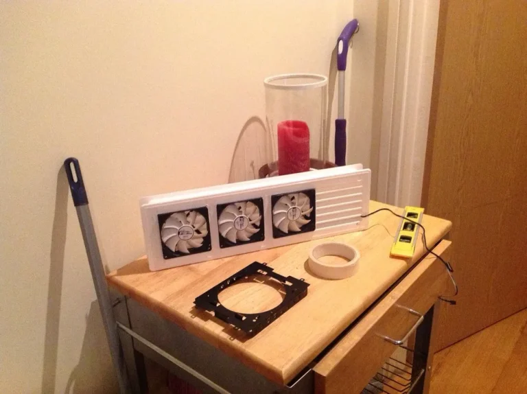 Two movers use moving straps to carry a wooden dresser through a narrow hallway with low clearance.