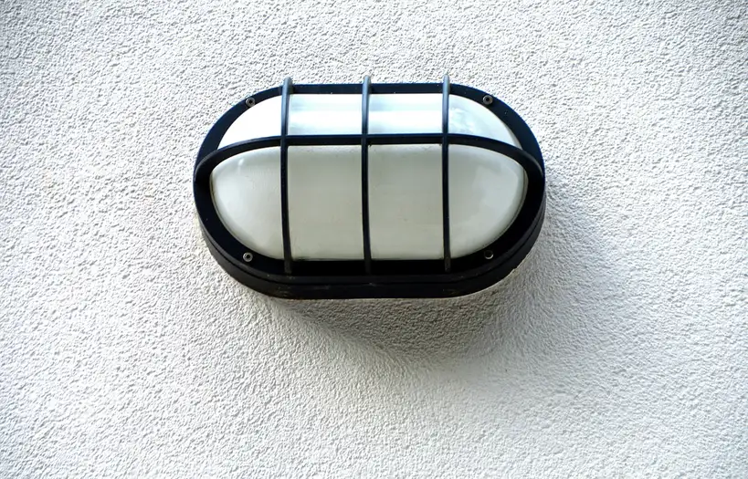 Outdoor wall lights on a front porch beside the door and columns at golden hour