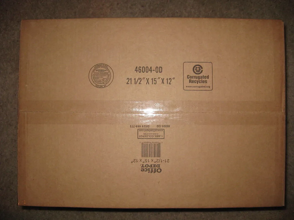 A wrapped wooden table leg being packed into a corrugated shipping box with cushioning