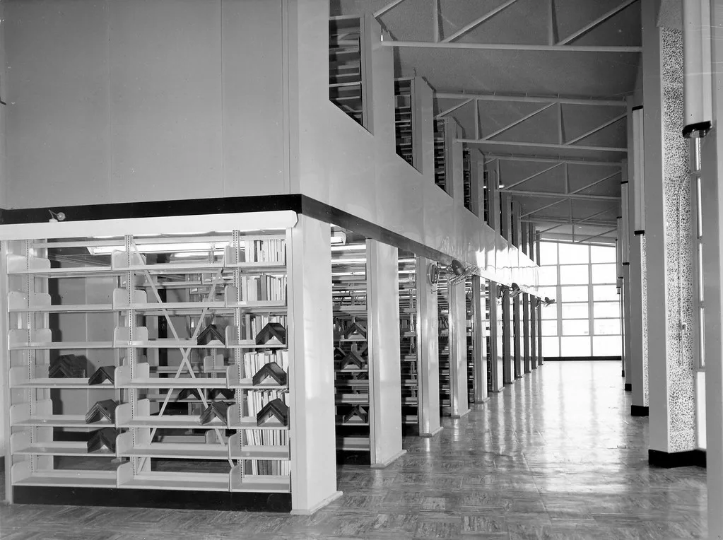 Hand opening a bookshelf with doors to reveal neatly stored books