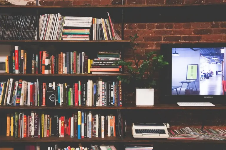 A freestanding bookshelf beside wall shelves in a bright living room with books and decor