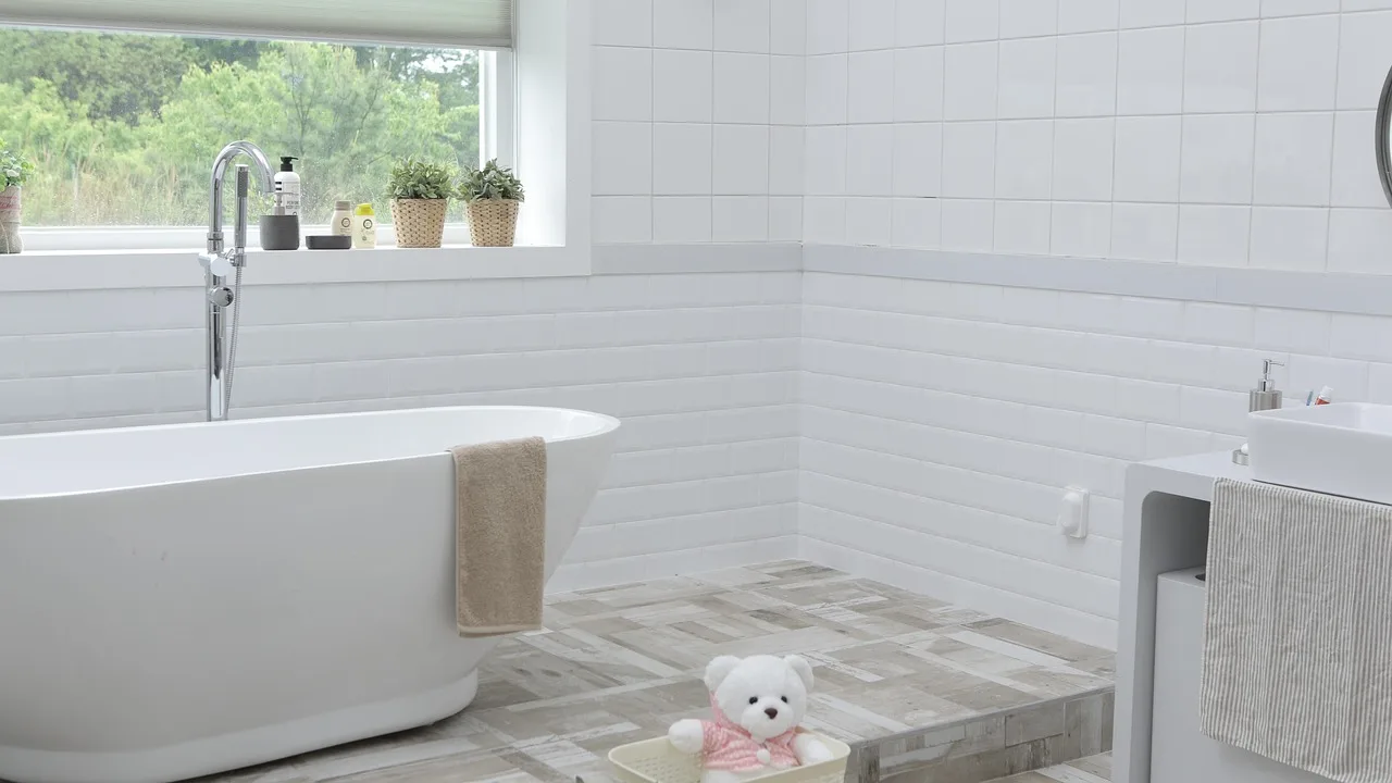 A person cleaning a bathtub and faucet in a bright bathroom with cleaning supplies nearby.