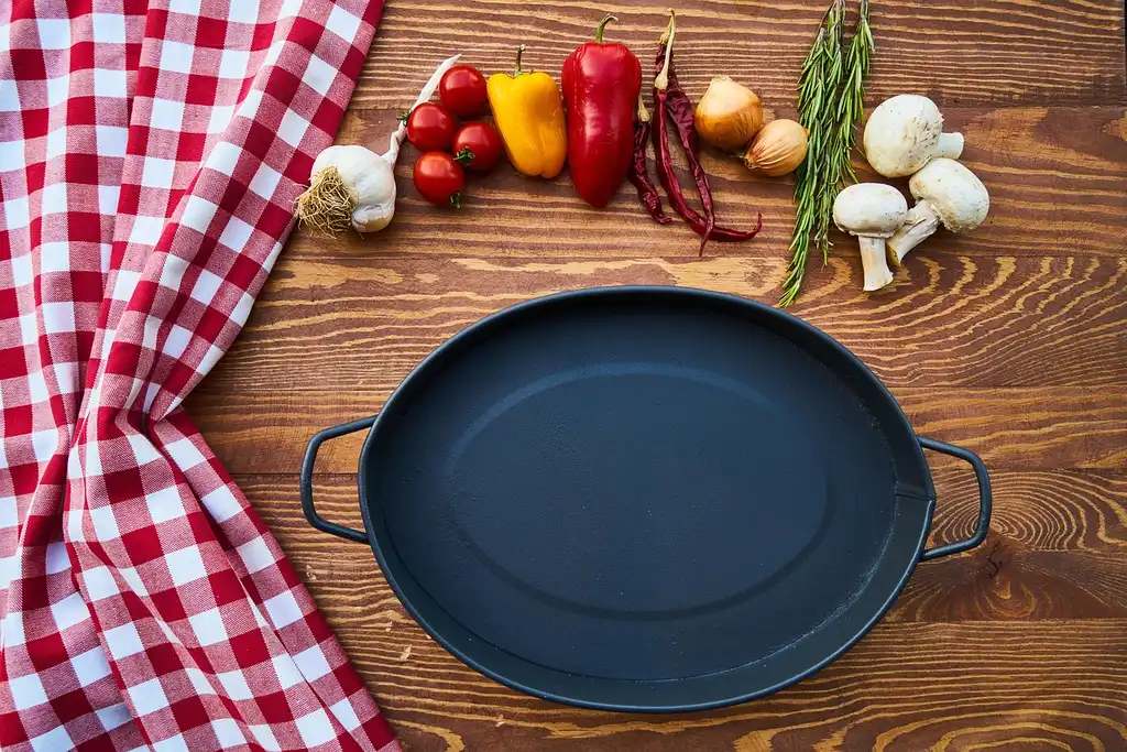 Caraway cookware set on a kitchen counter beside a stovetop with vegetables cooking