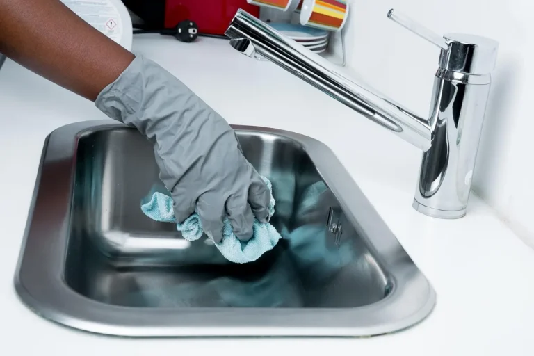 Cookware cleaning brush beside stainless steel, cast iron, and nonstick pans on a kitchen counter
