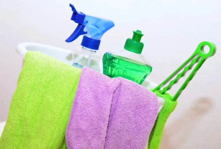 Cookware cleaning brush beside stainless steel, nonstick, and cast iron pans in natural light