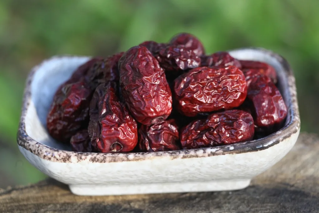Hand slicing a Medjool date for baking beside chopped dates and flour