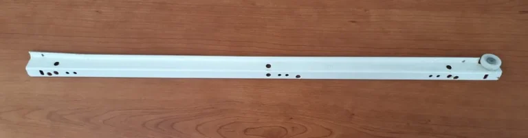 Drawer slide samples on a workbench beside an open cabinet and measuring tools