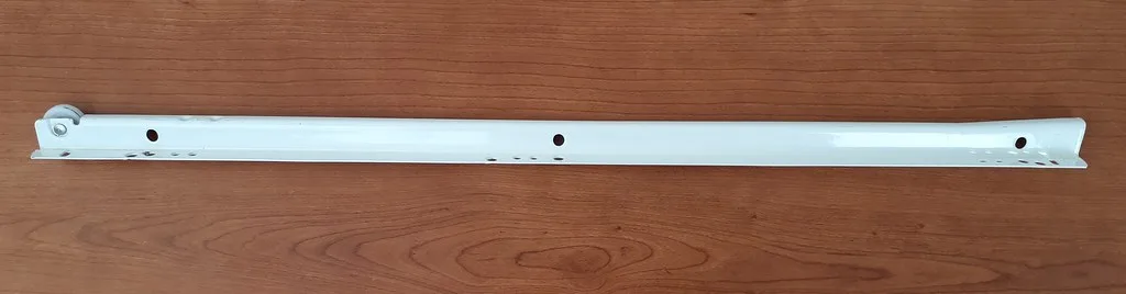 Hand installing a drawer slide on a kitchen drawer box with screws and a drill