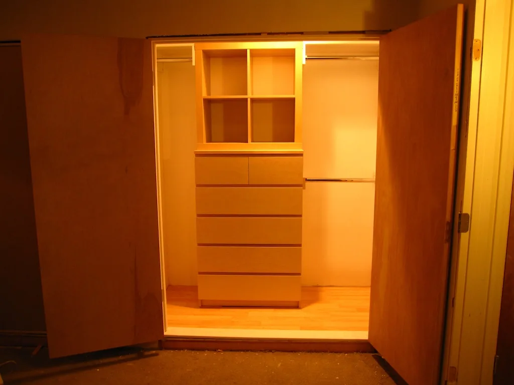 Person checks a sticky dresser drawer beside worn hardware in a sunlit bedroom.