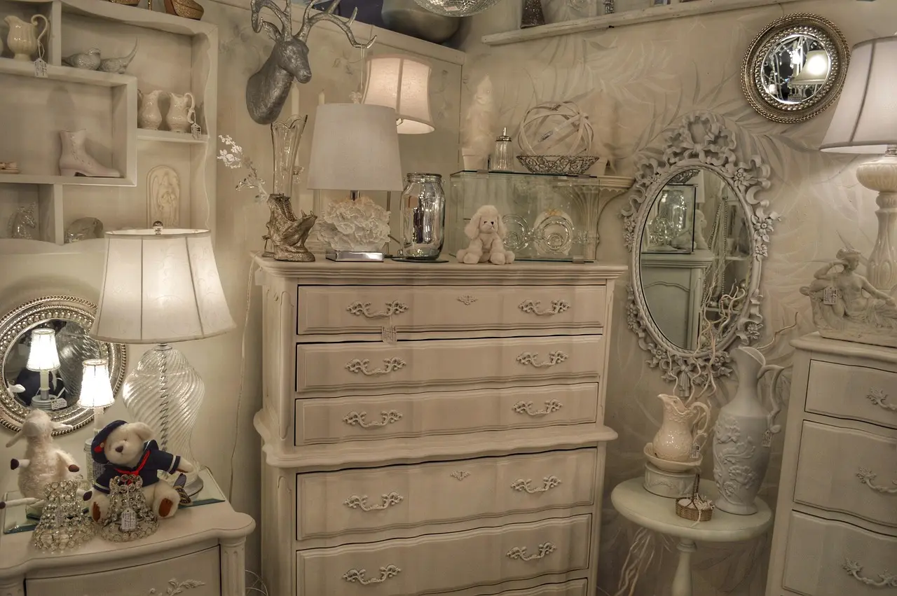 Mirrored dresser in a small bedroom beside a bed with a narrow walkway and natural light