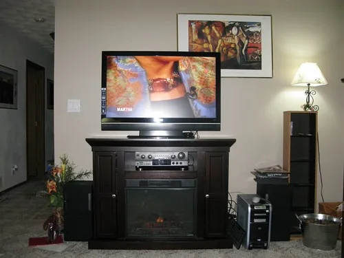 Living room with a fireplace TV stand beside a standard TV stand for comparison