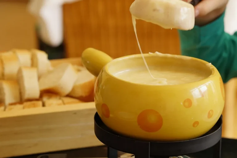 Fondue pot and small slow cooker on a candlelit table for two with dipping food and wine glasses