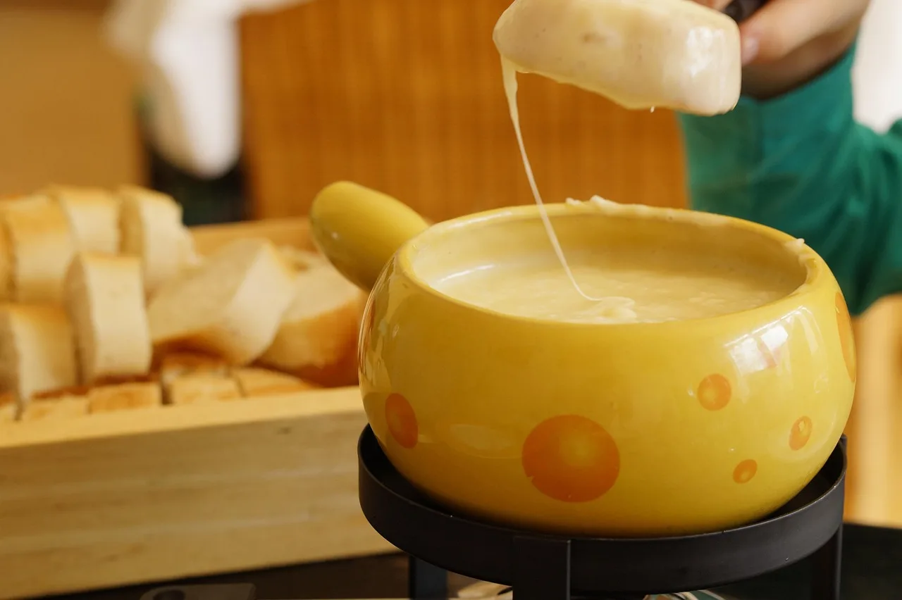 Fondue pot and small slow cooker on a candlelit table for two with dipping food and wine glasses
